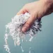 A hand holds shredded paper that can be composted.