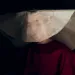 A woman wears a burgundy dress and white hat inspired by The Handmaid's Tale.