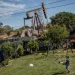 A young boy kicks a soccer ball in a backyard in Wilmington, LA. Just over the fence is a pumpjack.