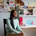 Shreya Ramachandran sits in a chair in her room smiling