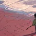 Illustration shows a small African American girl drawing a house in the sand next to the ocean