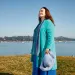 Mary Crowley, wearing bright blue and turquoise, stands by the bay in Sausalito.