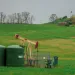 A gas well sits in a big green field.