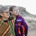Jessie and Verma Harrison stand together, both wearing blankets around their shoulders and looking off in the distance.