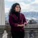 Mishka Banuri stands on a stone balcony with snowy mountains in the background, in Utah