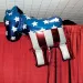 A helium donkey balloon with stars and stripes hangs next to a red curtain