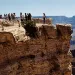 Close-up of a ledge in the Grand Canyon. People are looking over the edge and taking photos.