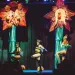 Nate and Hila perform "Plant Sex" at the House of Yes in New York. They are each sitting in a huge flower while people in insect costumes dance below.