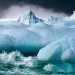 Waves splash against a blue iceberg in Antarctica