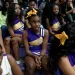 Several Uniontown Cheerleaders sit on bleachers wearing blue and gold Bobcats uniforms. Some wear gold ribbons in their hair.