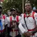 Several members of Team Onyx wear off-white shirts and red backpacks. One is holding a plastic bag with a compass and other items.