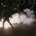 A cloud of tear gas silhouetting human figures against a night sky in downtown Portland, OR
