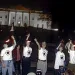 Women in white t-shirts eating fire in front of the White House in the night.