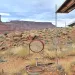 A desert landscape with red mesas in the background, and small terra-cotta circles around segments of the desert.