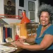 Portrait of American author Toni Morrison smiling and sitting at her desk at home, 1980s.