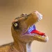 Close-up of brownish green plastic dinosaur with teeth bared.