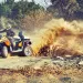 ATV driven by a guy in a helmet, kicking up an enormous plume of dust.
