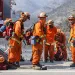 Firefighters in orange firefighting suits in front. of a hazy California landscape