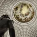 Big beige cream-colored dome of the Senate as seen from the inside with periwig sculpture in foreground.