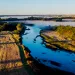 Aerial view of the West Nodaway River with agricultural fields surrounding it and blue skies above.