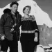 Black and white photo of a man and a woman standing on a glacier in the 1950s, looking dashing.