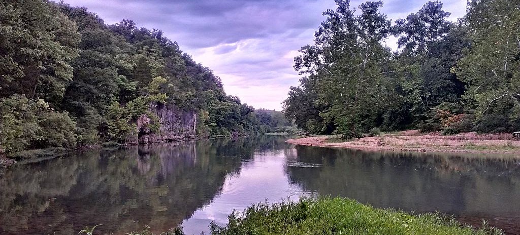 A landscape view of the Meramec River in August 2012 featuring tree lined banks and calm waters flowing.