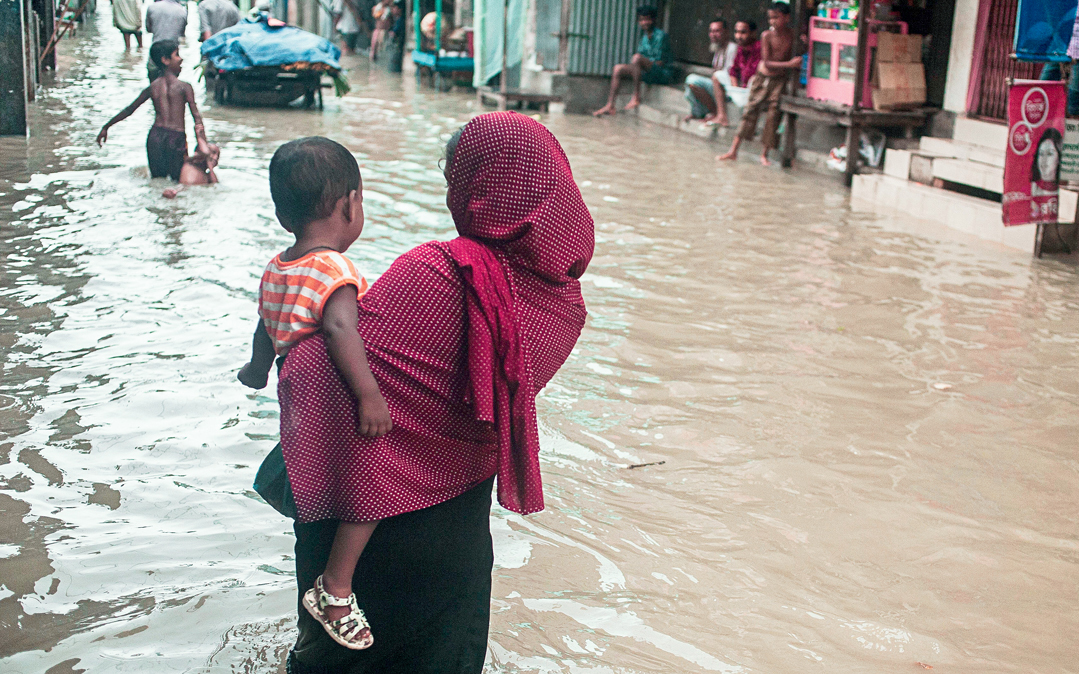 A mother and child cross a flooded street in Chittagong, Bangladesh.