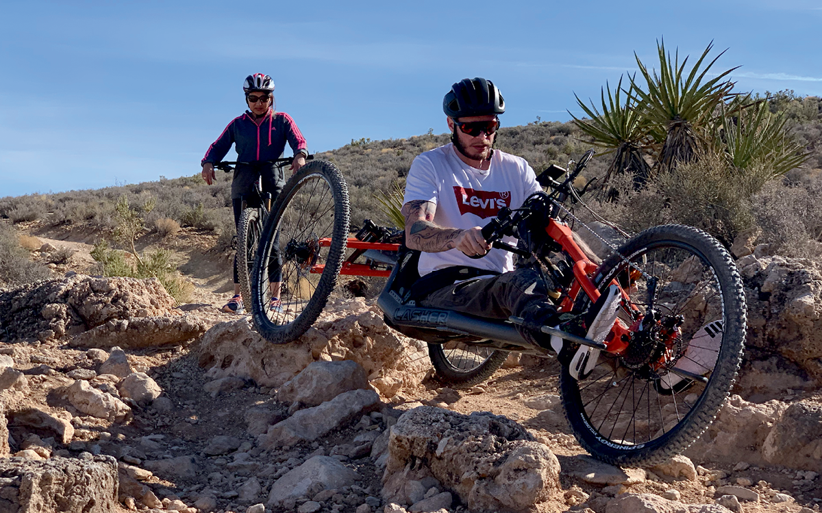 Two people are biking on rocky terrain. One of them is riding a Lasher Sport ATH-FS mountain bike.