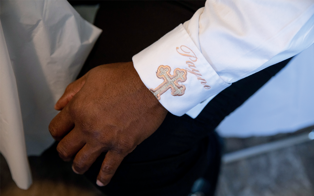 Close-up of the cuff of Pastor Demetrius Payne's crisp white shirt, which is monogrammed with "Payne" and a cross.