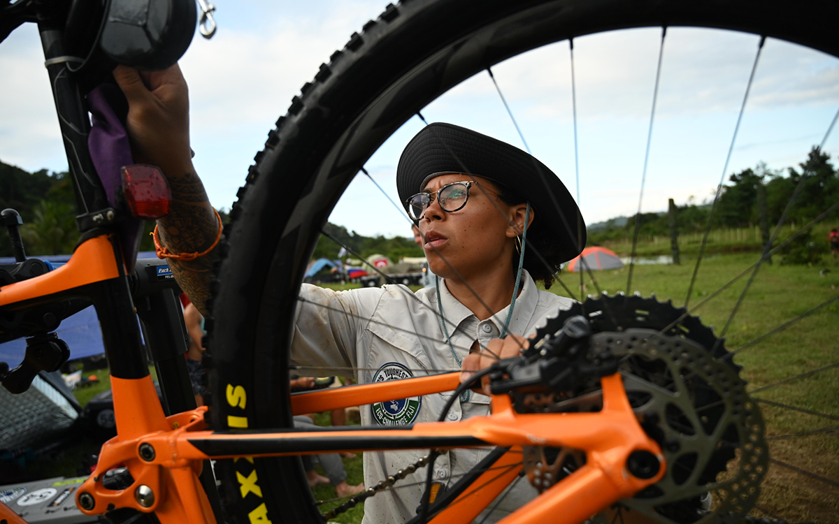 A member of Team Onyx is wearing glasses and inspecting an orange bike.