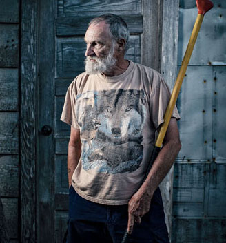 Outside his well house, Ted Haviland holds an oar he built from two broken paddles; its length allows him to canoe standing up.