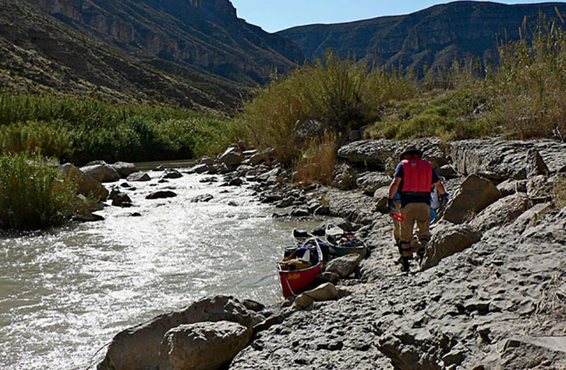 Lining a canoe through a rapid that could not be run because of low water.