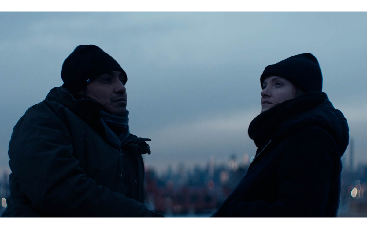 Two figures bundled up in winter clothes on a roof, silhouetted against the sky.