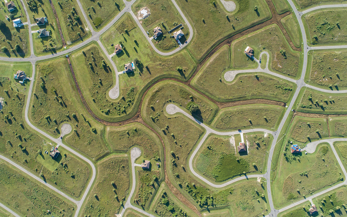 Arial view of a matrix of roads and cul-de-sacs that form an unfinished subdivision encroaching on the Florida Wildlife Corridor