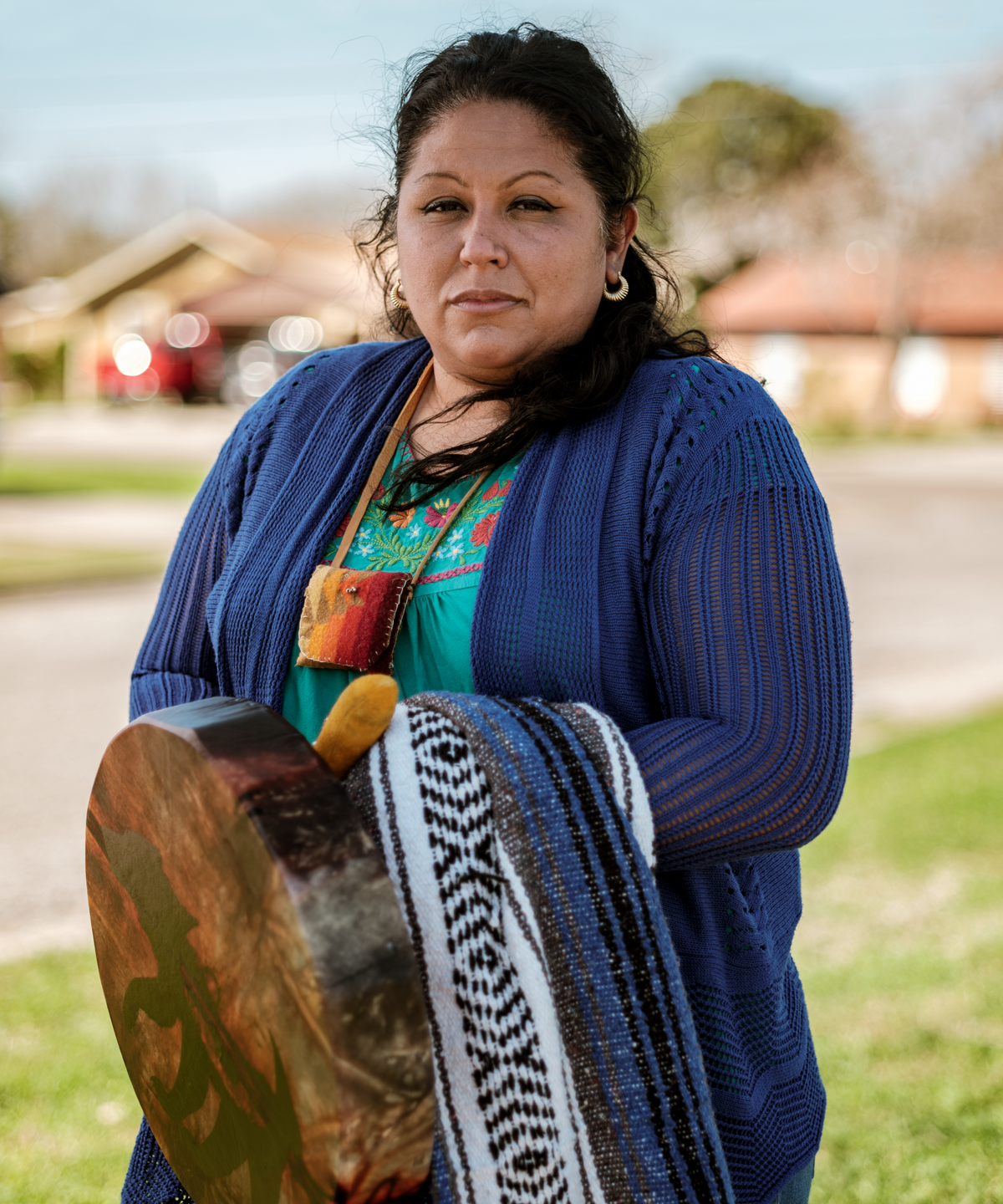 Love Sanchez looks at the camera, wearing a blue cardigan and holding a drum and blanket in front of her.