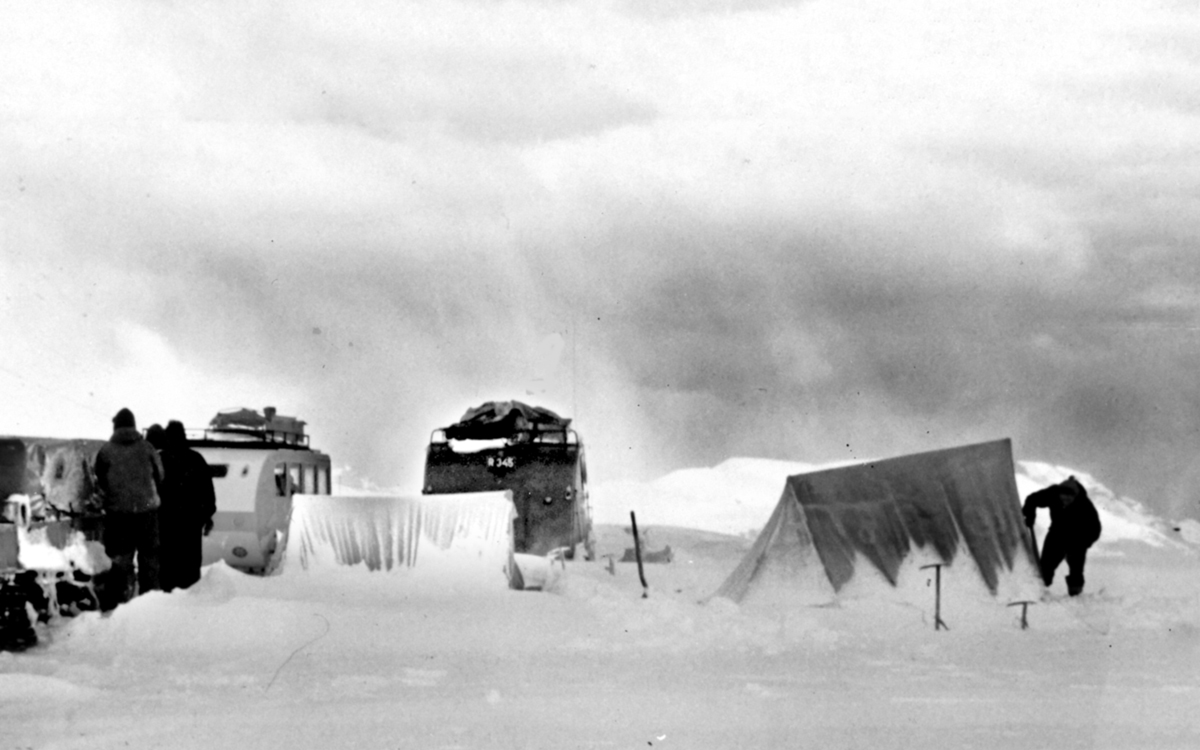 Black and white photo, taken in the 1950s, of tents huddled together on a glacier.