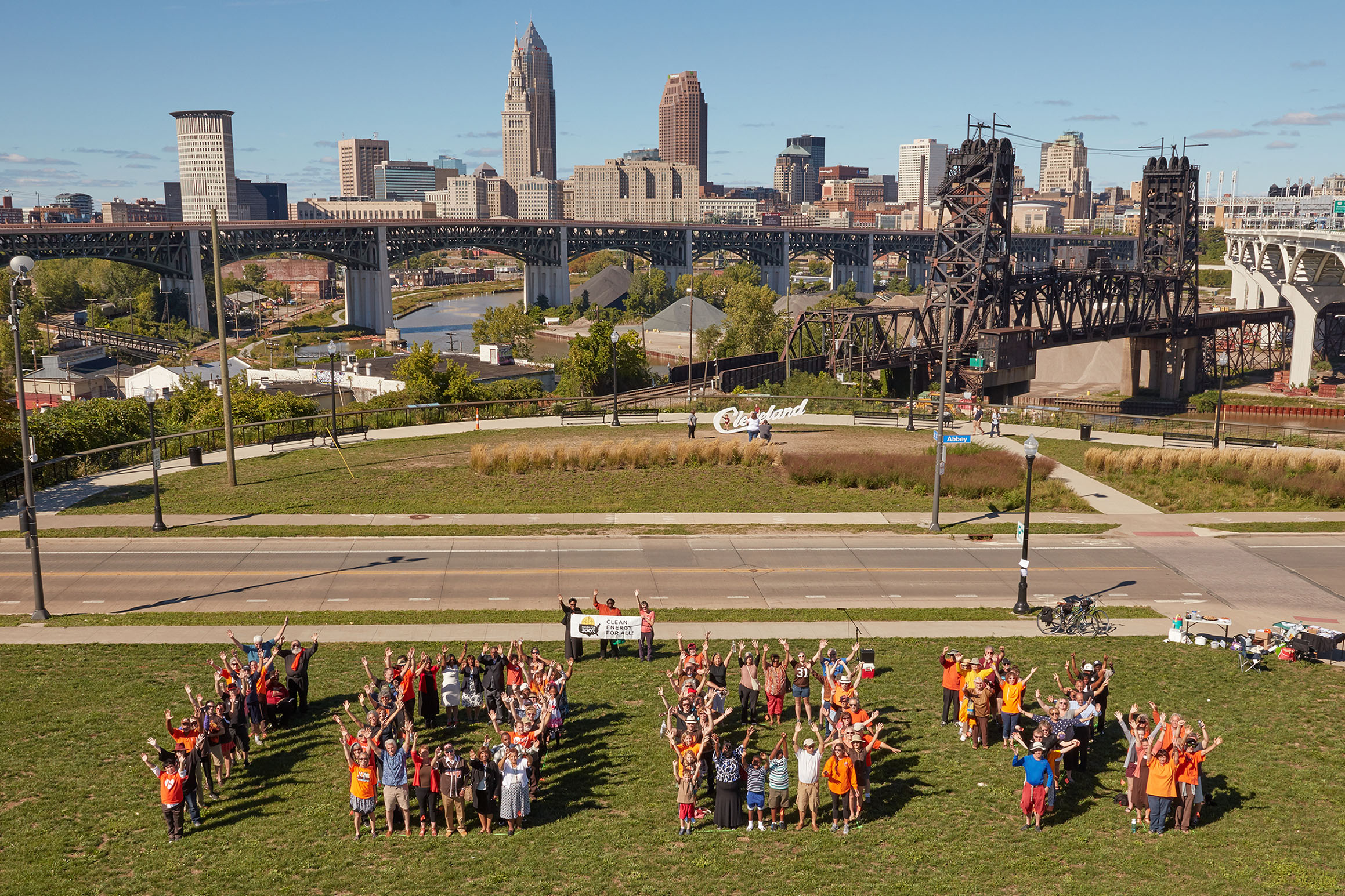 People stand in groups that spell out 100%, with a cityscape in the background.