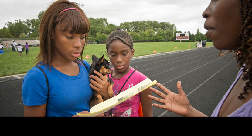 From right: Alisha Winters invites Kamajia and Kerriona Corbin to a Sierra Club–sponsored community meeting featuring University of Michigan professors who published a study showing how air pollution affects children's health and academic scores throughou