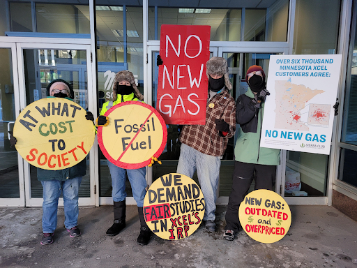 People hold up signs calling for clean energy and no new gas plants. 