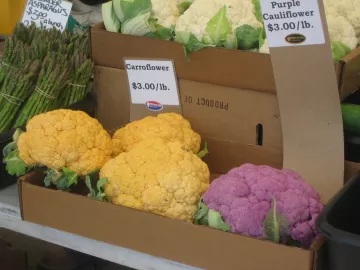 Several types of cauliflower on sale at a farmer's market.